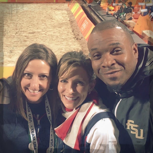 Gina Pongetti Angeletti with a friend and a man in an FSU jacket in the stands above the beach volleyball court.